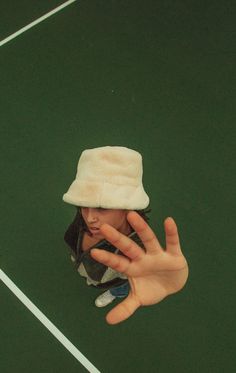 a person wearing a white hat and holding their hand up to the camera