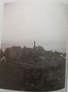 an old photo of a person standing on top of a rock outcropping