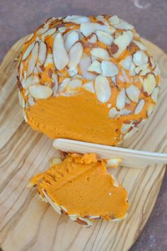 a wooden plate topped with a piece of cake covered in almonds and orange frosting