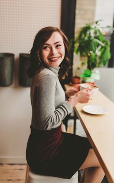 a woman sitting at a table with a plate in her hand and smiling for the camera