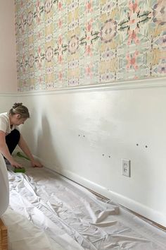 a woman is painting the wall with white paint