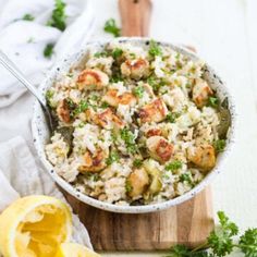 a bowl filled with rice, shrimp and parsley on top of a cutting board