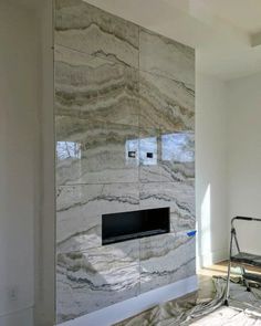 an empty room with a chair and a fireplace in it's center wall that is made of marble