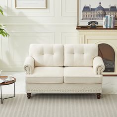 a white couch sitting next to a table with a plant on top of it in a living room