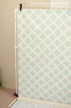 a white and blue wall hanging on the side of a room next to a bed