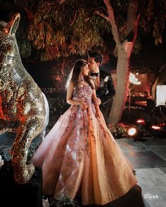 a man and woman standing next to each other in front of a tree at night