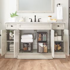 a white bathroom vanity with two sinks and baskets under the sink area, along with other items