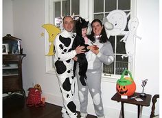 a man and woman are dressed up in halloween costumes while holding their child, who is wearing a cow costume