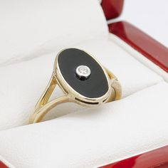 a ring with a black and white stone on it in a red velvet gift box