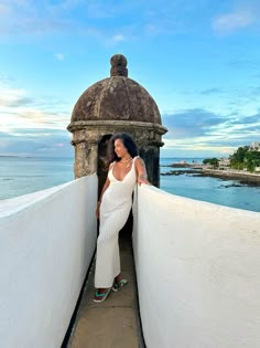 a woman in white dress leaning against the wall