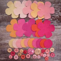 several different colored flowers and buttons on a wooden surface