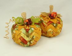 two decorative pumpkins with leaves and berries on them are sitting side by side in front of a white background