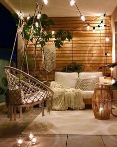 an outdoor living room with hanging plants and lights on the wall, along with a hammock chair