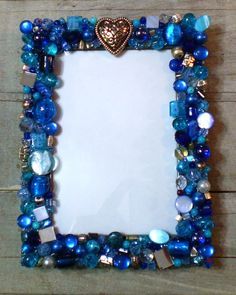 a blue and white beaded photo frame with a heart on the top, surrounded by other beads