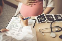 a pregnant woman sitting at a table with her doctor in the background holding a clipboard