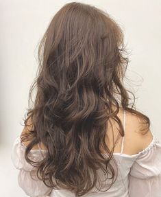 the back of a woman's head with long, wavy hair and white blouse