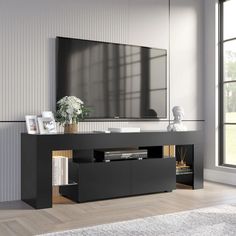 an entertainment center with a large flat screen tv on it's stand in front of a window