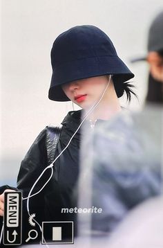 a woman wearing a black hat and listening to headphones