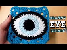 someone is holding up a crocheted square with an evil eye on the front