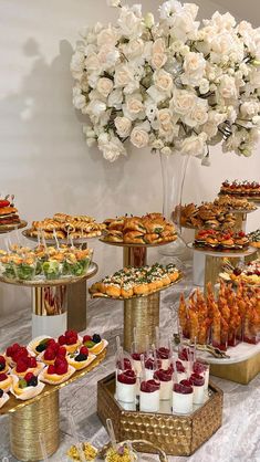 a table topped with lots of desserts next to a tall vase filled with flowers