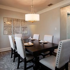 a dinning room table with white chairs and a chandelier hanging from the ceiling