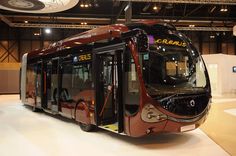 a red and black bus is on display in a building with white flooring that has lights hanging from the ceiling