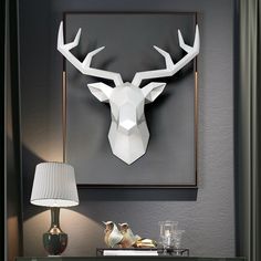 a white deer head mounted to the side of a wall next to a night stand