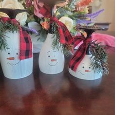 three white vases with red and black plaid bows on them sitting on a table