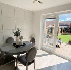 a dining room table with four chairs next to a sliding glass door