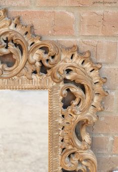 an ornate wooden mirror hanging on a brick wall