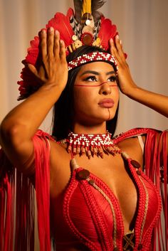 a woman in a red costume with feathers on her head and hands behind her head