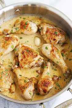 a pan filled with chicken and onions on top of a table next to utensils