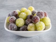 a white bowl filled with fruit covered in powdered sugar on top of a table