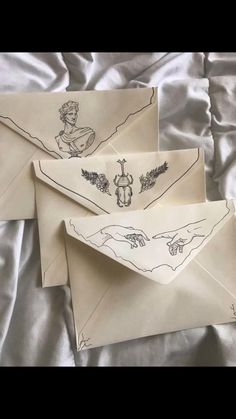 three envelopes with drawings on them sitting on a bed