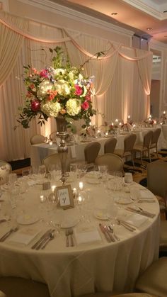 a table set up for an event with white linens and floral centerpieces