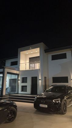 two cars parked in front of a house at night