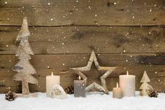 a wooden table topped with candles next to a christmas tree and snow covered stars on top of it