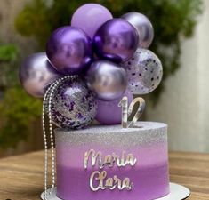 a purple and silver cake with balloons on top that says marra clora in spanish