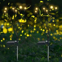 two solar powered lights in the grass with yellow bokets behind them and green foliage