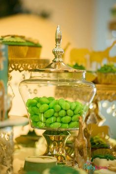 green candy balls in a glass bowl on a table with other items and decorations behind it