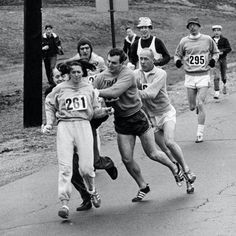 a group of men running down a road next to each other