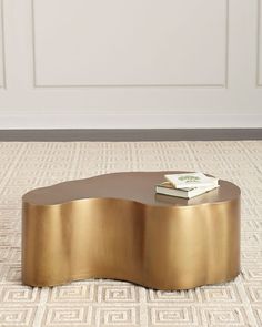 a gold coffee table with books on it in front of a white wall and door