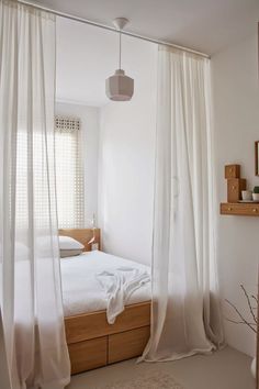 a white bedroom with sheer curtains hanging from the ceiling