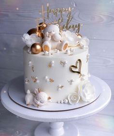 a white cake with gold decorations and teddy bears on top