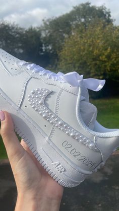 someone is holding up a white nike air force shoe with pearls on the upper part