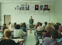 a woman standing in front of a class room full of people