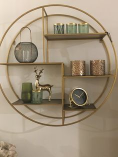 a gold circular shelf with candles, vases and a clock on it's side