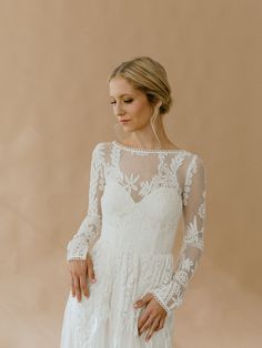 a woman in a white wedding dress with long sleeves and sheer lace on her shoulders