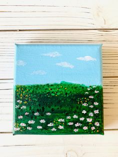 an acrylic painting of a green field with white daisies and blue sky