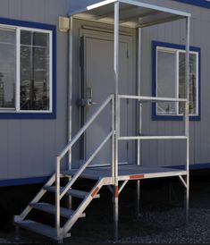 a small building with stairs leading up to the door and windows on top of it